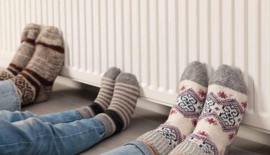 Tres personas apoyando los pies en un radiador