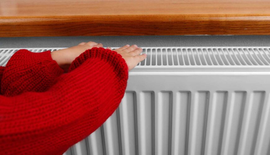 Niña colocando las manos encima de un radiador
